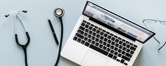 laptop computer and stethoscope on desk